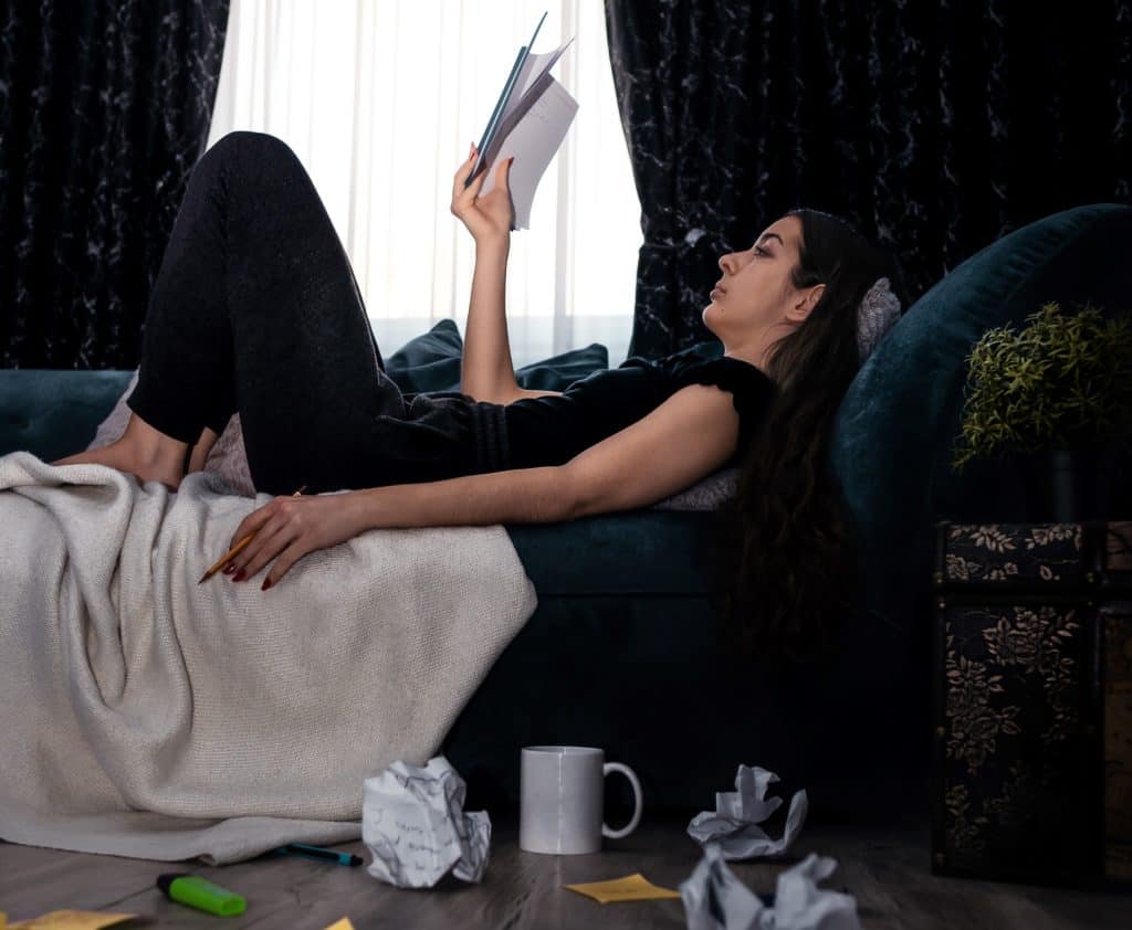 a photo of a girl lying on a bed and reading a book