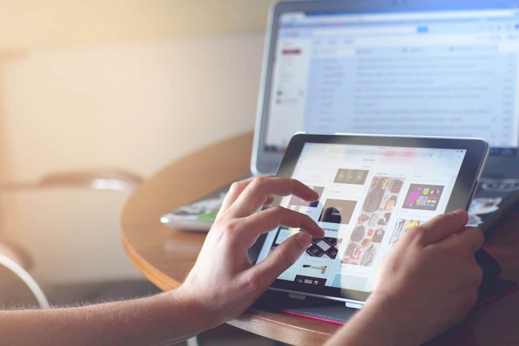 an image of a person holding an ipad while working on a computer