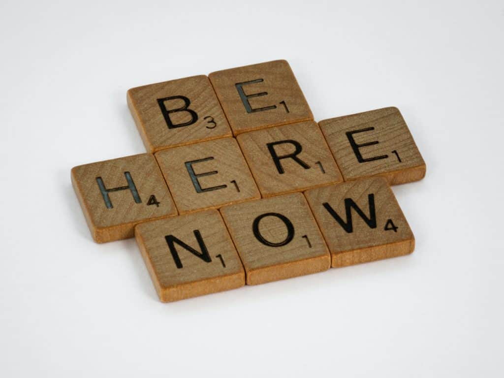 scrabble pieces spelling "be here now"