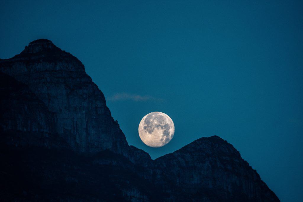 a photo of a mountain with the moon in the background