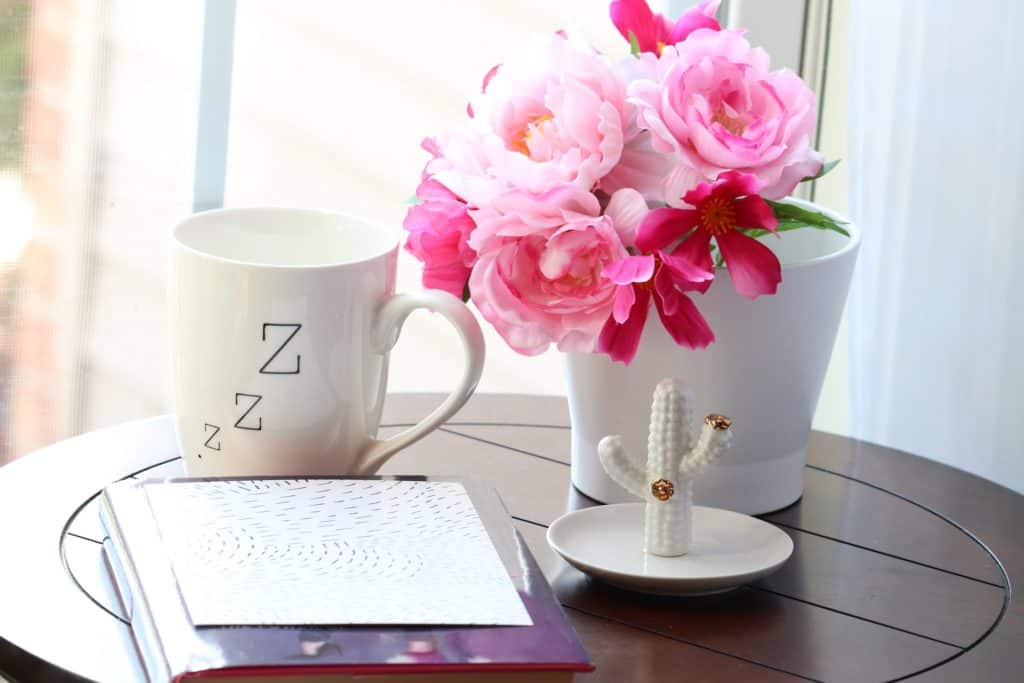 A photo of a table with a coffee cup and a floral bouquet