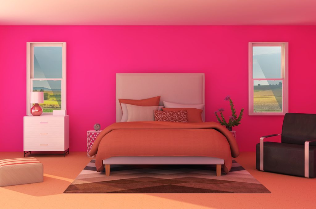 A bedroom with apink wall and orange bedding