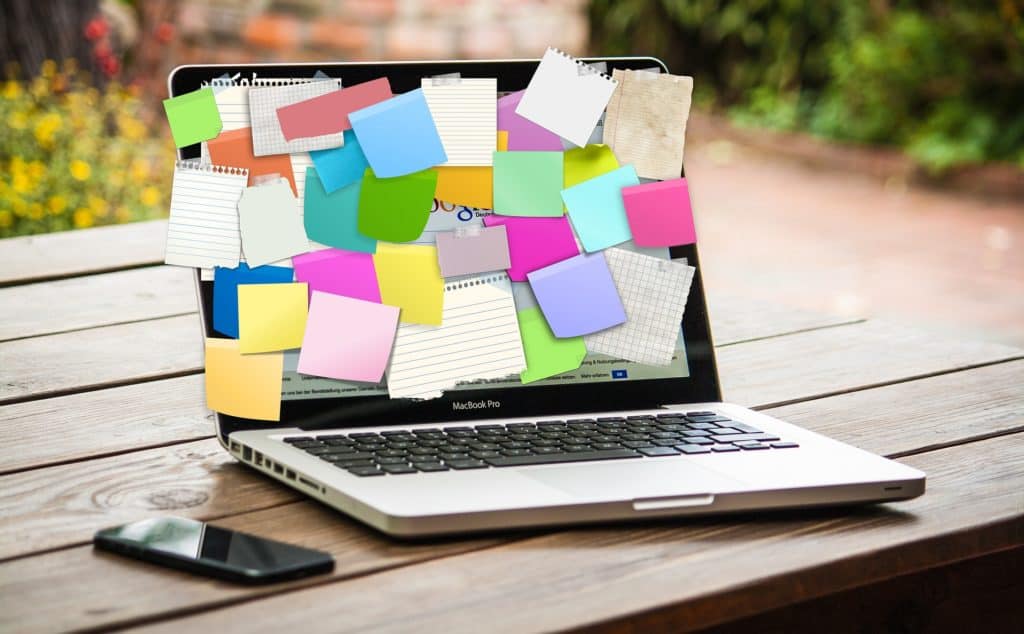 A photo of a macbook with colorful post it notes goals on the screen