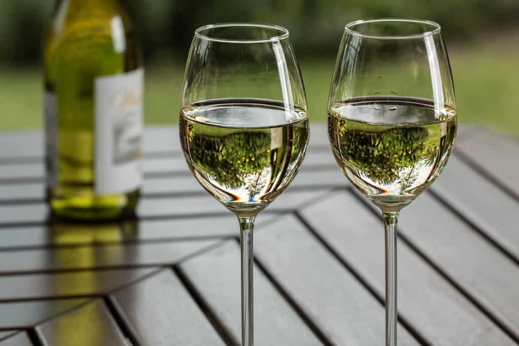 An image of two goblets of white wine on a patio table