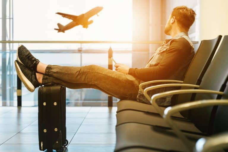 A photo of a person in an airport with jet lag watching a plane take off